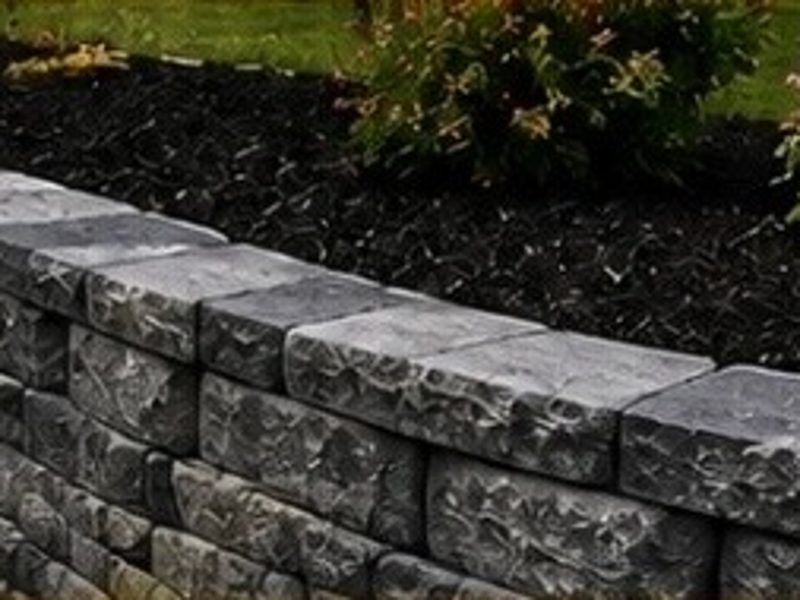 Curved grey block wall beside a mulched planting bed